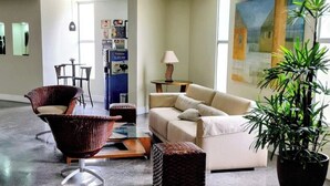 Un hall d’entrée spacieux au design moderne, comprenant un coin salon avec un canapé et des fauteuils, une table basse et une grande plante en pot.