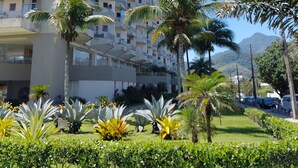 Un hôtel à plusieurs étages doté de balcons, entouré de palmiers et avec une montagne en toile de fond.