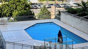Une piscine avec vue sur l’océan, entourée de palmiers et disposant d’un espace de stationnement.