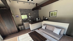 A modern living room with a sofa, coffee table, and kitchen in the background. - Guest Villa Hakone Kazamatsuri (Odawara)