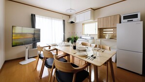 A modern kitchen with a dining area, wooden cabinets, a refrigerator, and a flat-screen TV. - Guest Villa Hakone Kazamatsuri (Odawara)