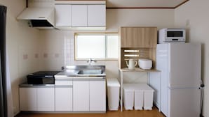 A compact kitchen with white cabinets, a stainless steel sink, a microwave, and a refrigerator. - Guest Villa Hakone Kazamatsuri (Odawara)
