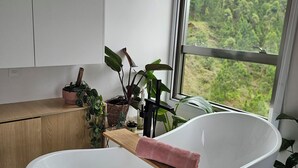 A modern bathroom with a freestanding bathtub, wooden shelves, and potted plants. - Sunrise apartment (Itajaí)