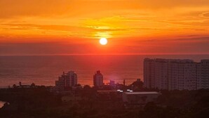 A sunset over a coastal cityscape with buildings and a clear sky. - Sunrise apartment (Itajaí)