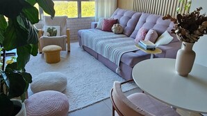 A modern living room with a sofa, ottomans, a dining table, and potted plants. - Sunrise apartment (Itajaí)