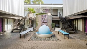 Un patio con una zona de estar central, dos escaleras y un edificio con balcón.