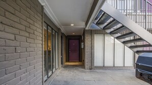 Un pasillo estrecho con una pared de ladrillo a un lado y una escalera de metal al otro.