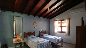 Un dormitorio con dos camas, techo de madera, ventana con cortinas y un espejo en la pared izquierda.
