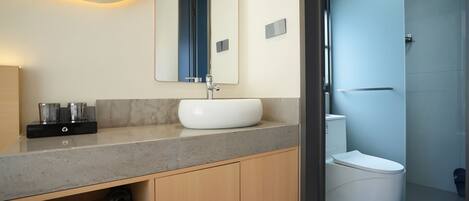 A modern bathroom with a marble countertop, a white sink, and a glass shower enclosure.