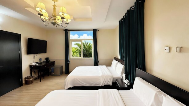 A hotel room with two beds, a desk, a TV, and a window with curtains. - JUN YUE Ikeja Lagos hotel (Lagos)