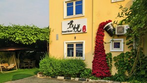 A hotel with a yellow facade, a sign indicating it's a Grand Hyatt, and a red flower wall. - JUN YUE Ikeja Lagos hotel (Lagos)