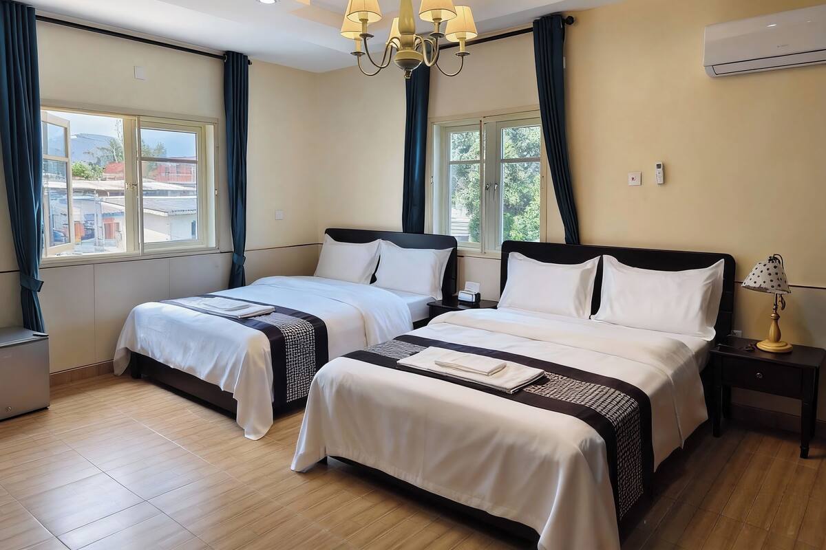 Habitación de hotel con dos camas, un candelabro, aire acondicionado y vistas al exterior.