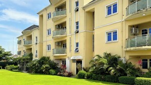 A multi-story residential building with balconies, air conditioning units, and a well-maintained lawn. - JUN YUE Ikeja Lagos hotel (Lagos)