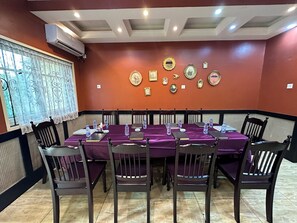 Uma sala de conferências com uma mesa comprida, cadeiras e uma parede decorada com fotografias emolduradas.