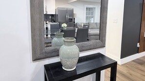 A modern living room with a large mirror, a black console table, and two vases.