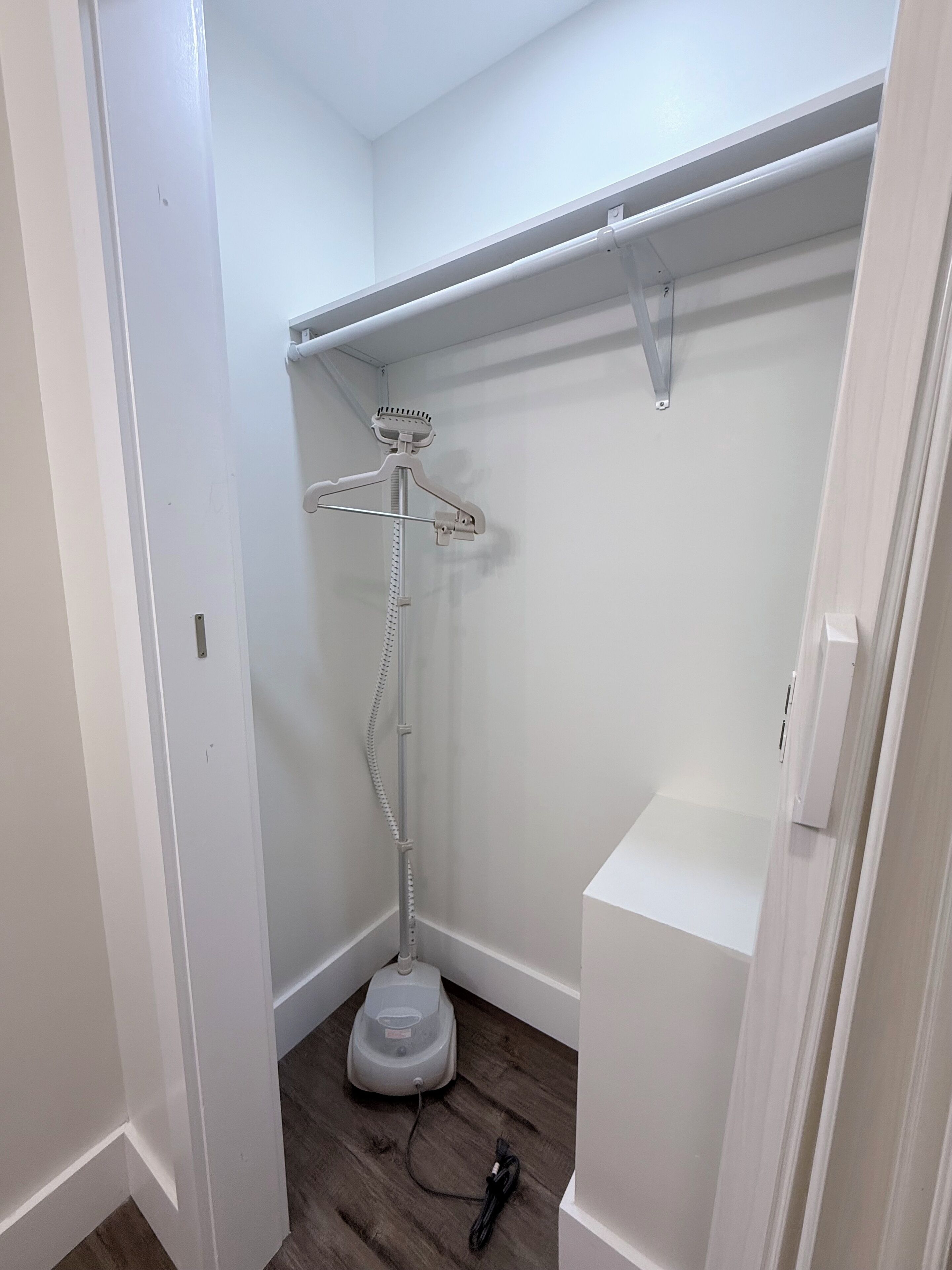 Een compacte kamer met witte wanden, een ingebouwde stofzuiger en een hangroede.