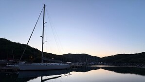 Un puerto deportivo con varios veleros amarrados, rodeado de colinas.