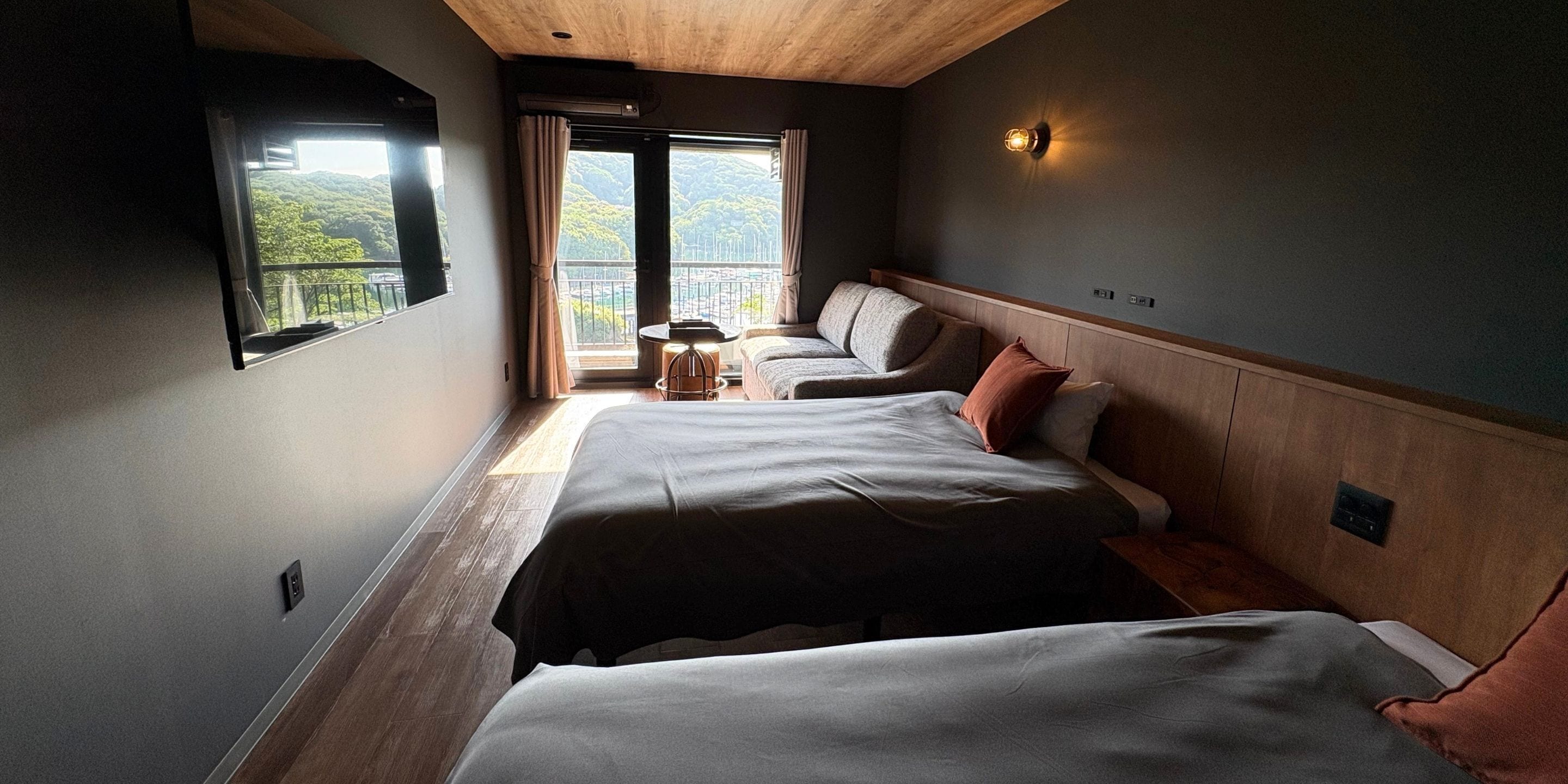 Habitación de hotel con dos camas, una mesita y vistas a un balcón.