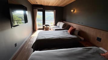 Habitación de hotel con dos camas, una mesita y vistas a un balcón.