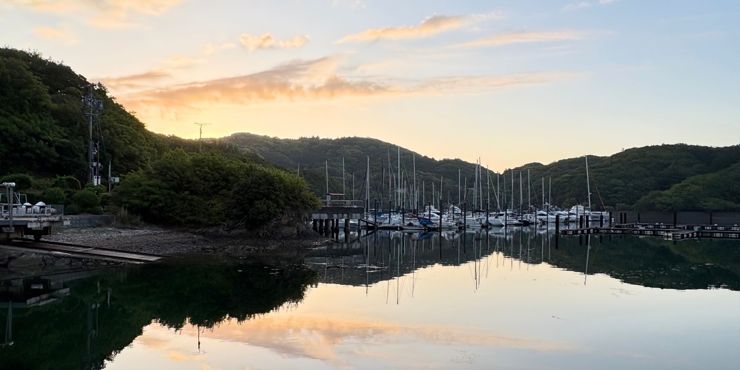 A marina with boats docked, surrounded by hills and a clear sky.