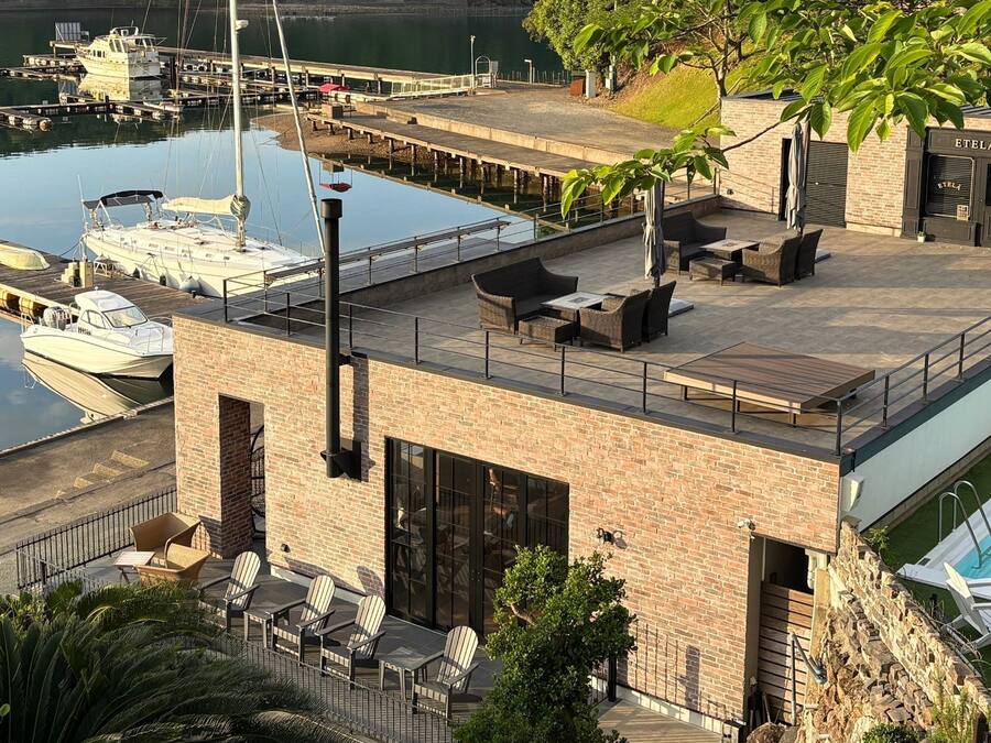 A rooftop terrace with a pool, lounge chairs, and a view of a marina with boats.