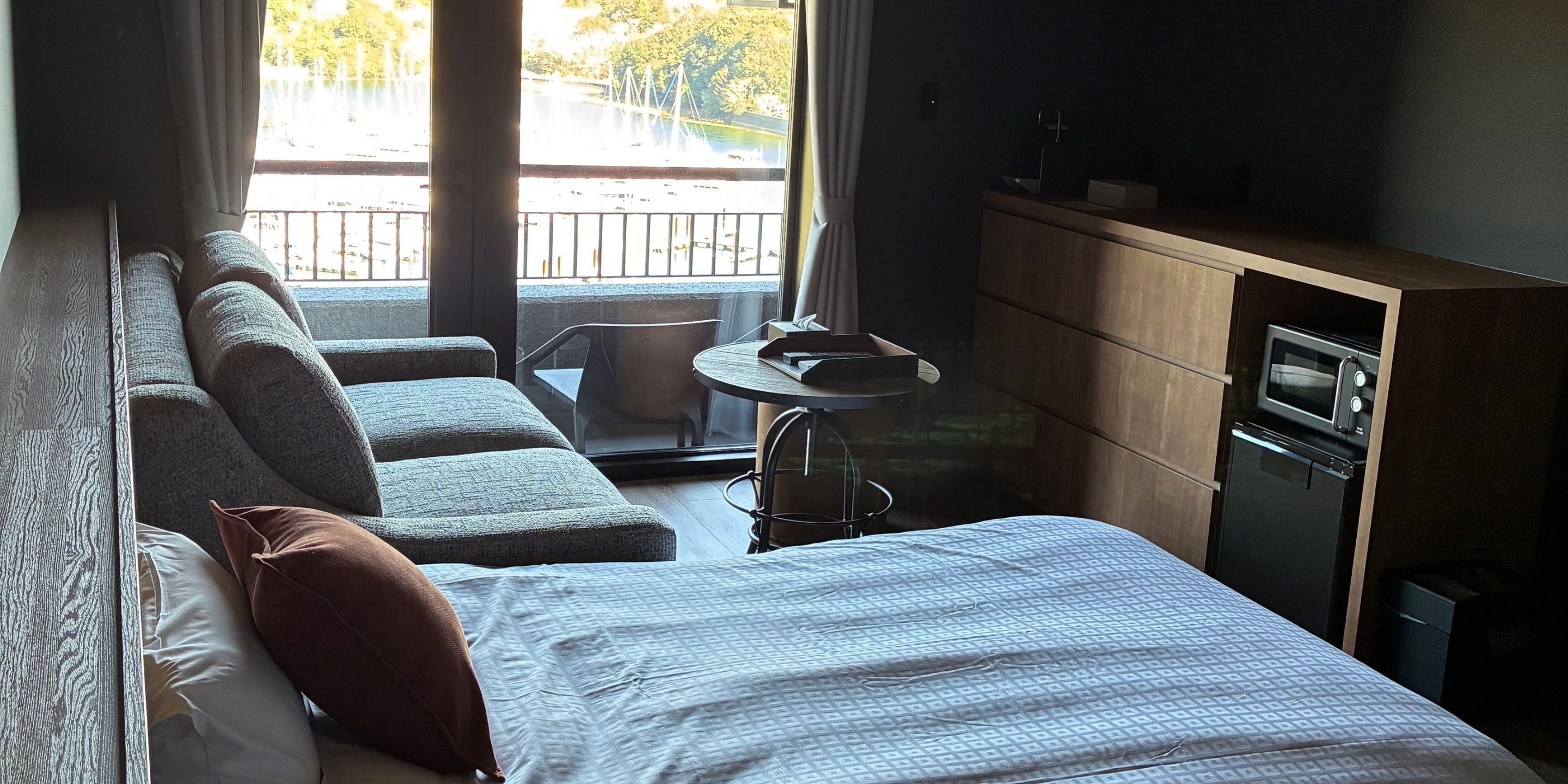 Una habitación de hotel con cama, sofá, una mesita y una kitchenette.
