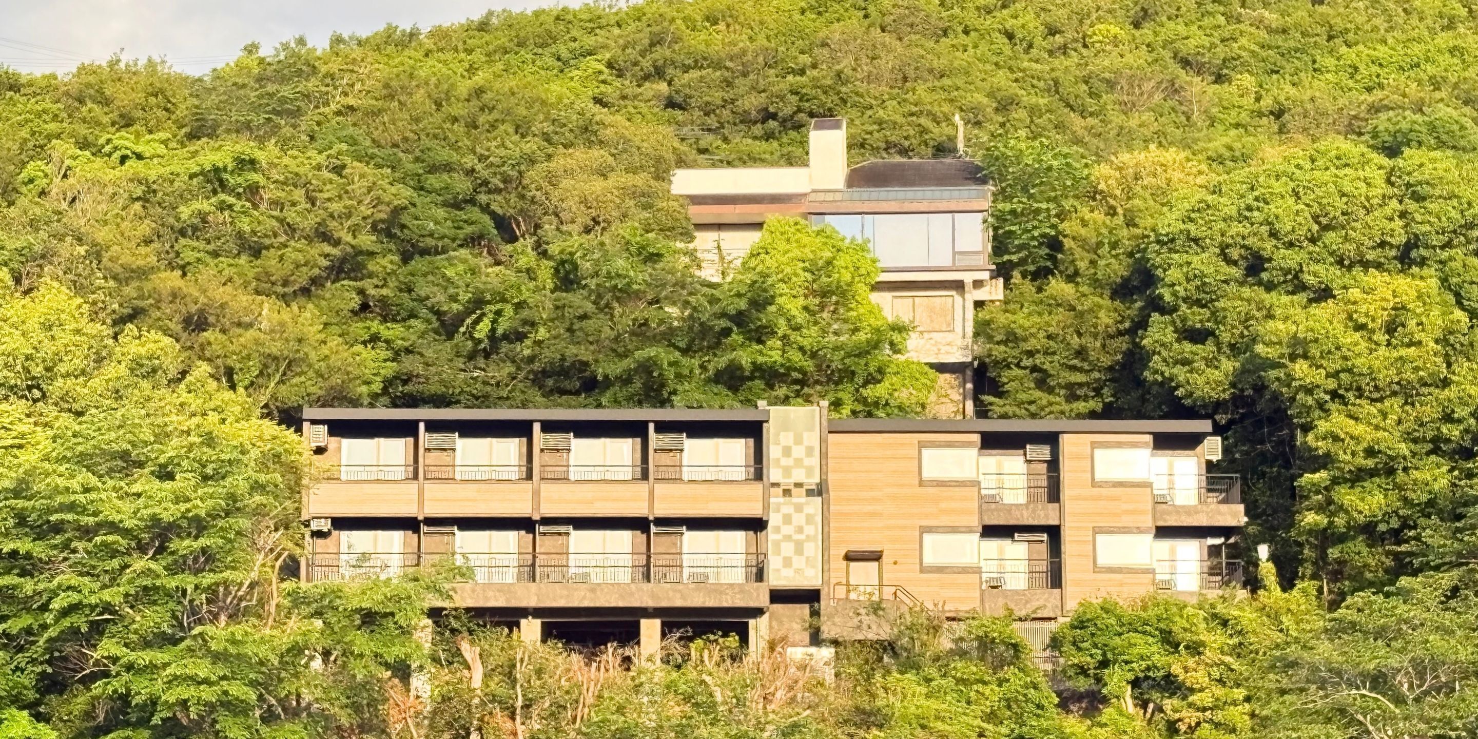 Un edificio moderno de varios pisos, rodeado de abundante vegetación.