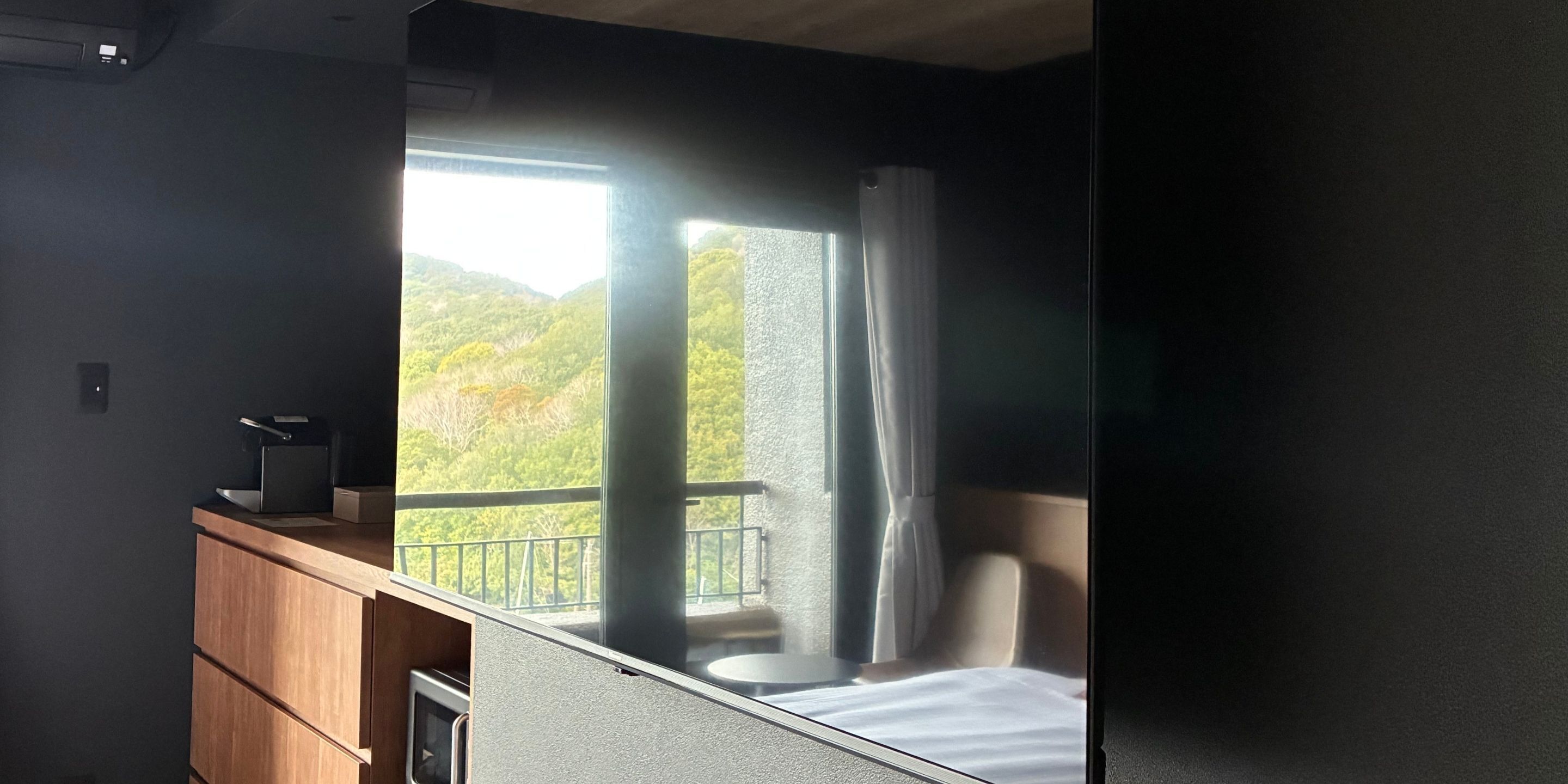 A room with a bed, a desk, and a window overlooking a mountainous landscape.