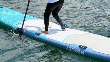 A person standing on a paddleboard with the brand name 'AZTRON' visible.
