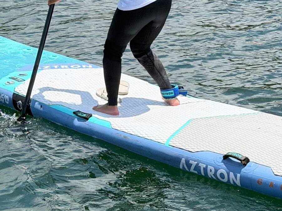 A person standing on a paddleboard with the brand name 'AZTRON' visible.