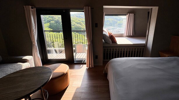 Habitación de hotel con una cama, una mesita y vista a un balcón con barandilla.