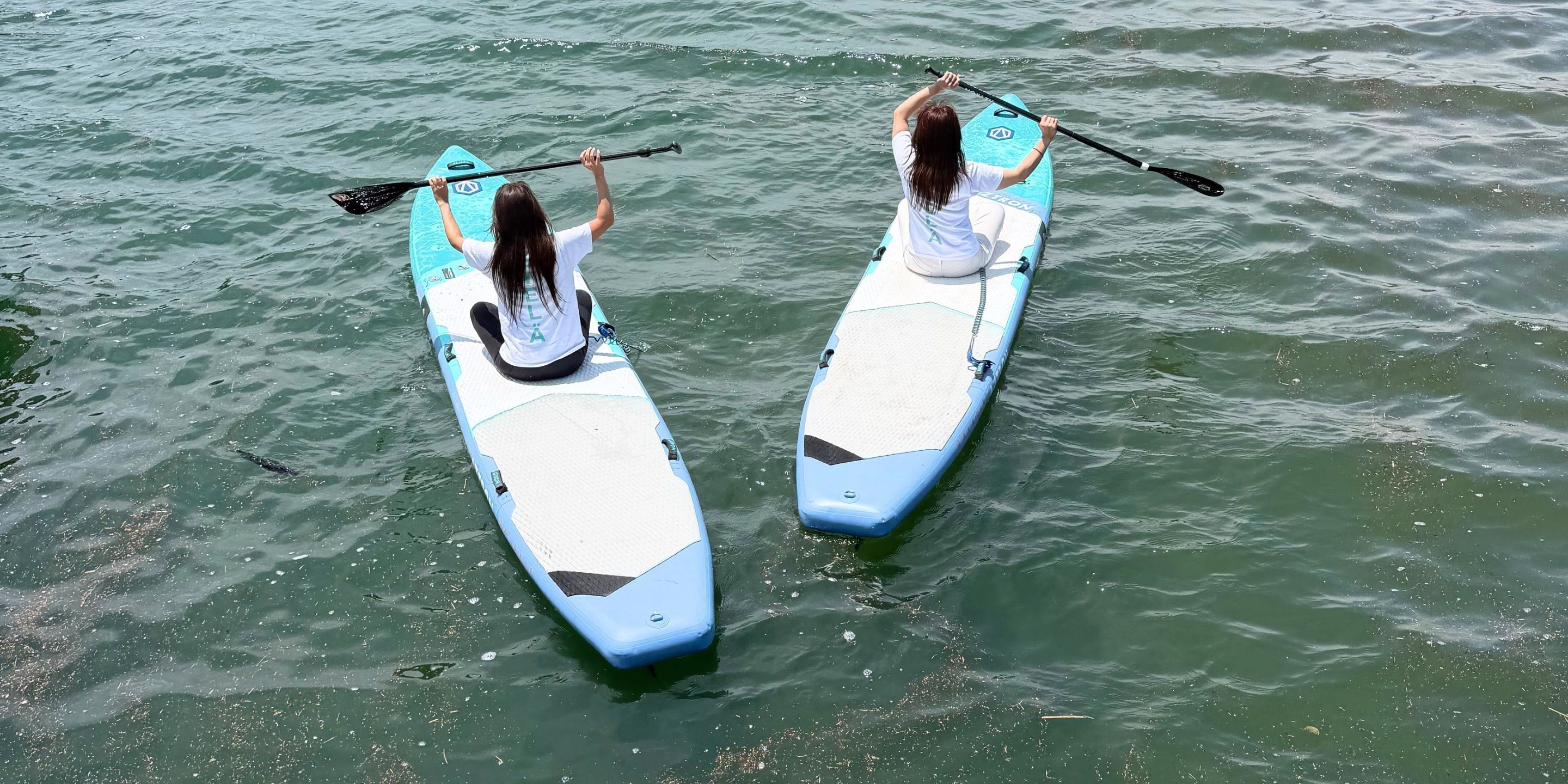 Two people paddling on a calm body of water.