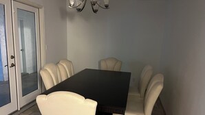 Ein Essbereich mit einem dunklen Holztisch, der von sechs beigefarbenen Stühlen umgeben ist.