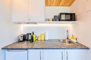 Eine kompakte Küche mit Mikrowelle, Toaster, Kaffeemaschine und Spüle.