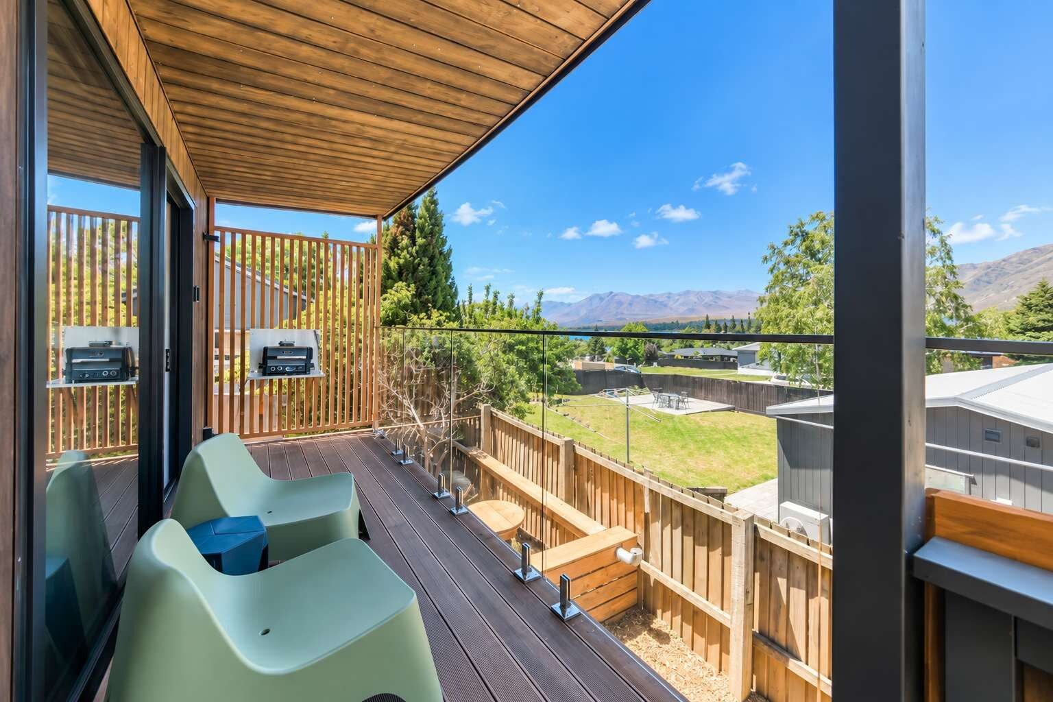 A covered outdoor deck with seating and a view of a mountainous landscape.