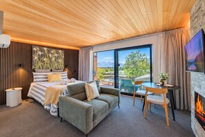 Een moderne hotelkamer met een bed, een bank, een eettafel en een open haard.