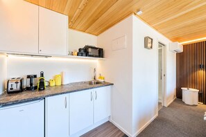 Een moderne keuken met witte kasten, een granieten aanrecht en diverse apparaten, waaronder een broodrooster, koffiezetapparaat en magnetron.