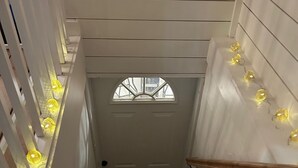 Eine Treppe mit Handlauf, eine Tür mit Fenster und dekorativer Wandbeleuchtung.