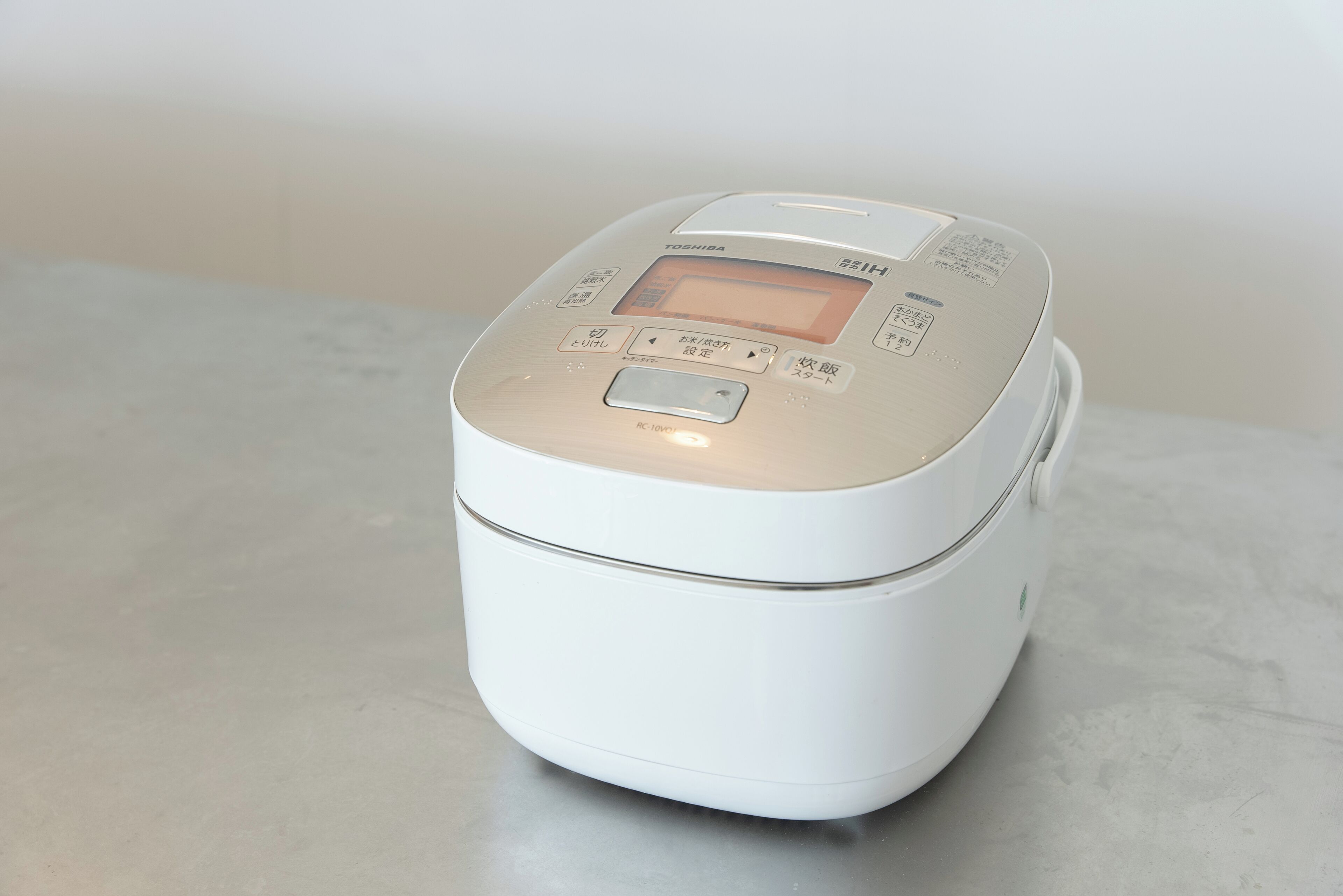 A white rice cooker with a digital display and buttons on the top.