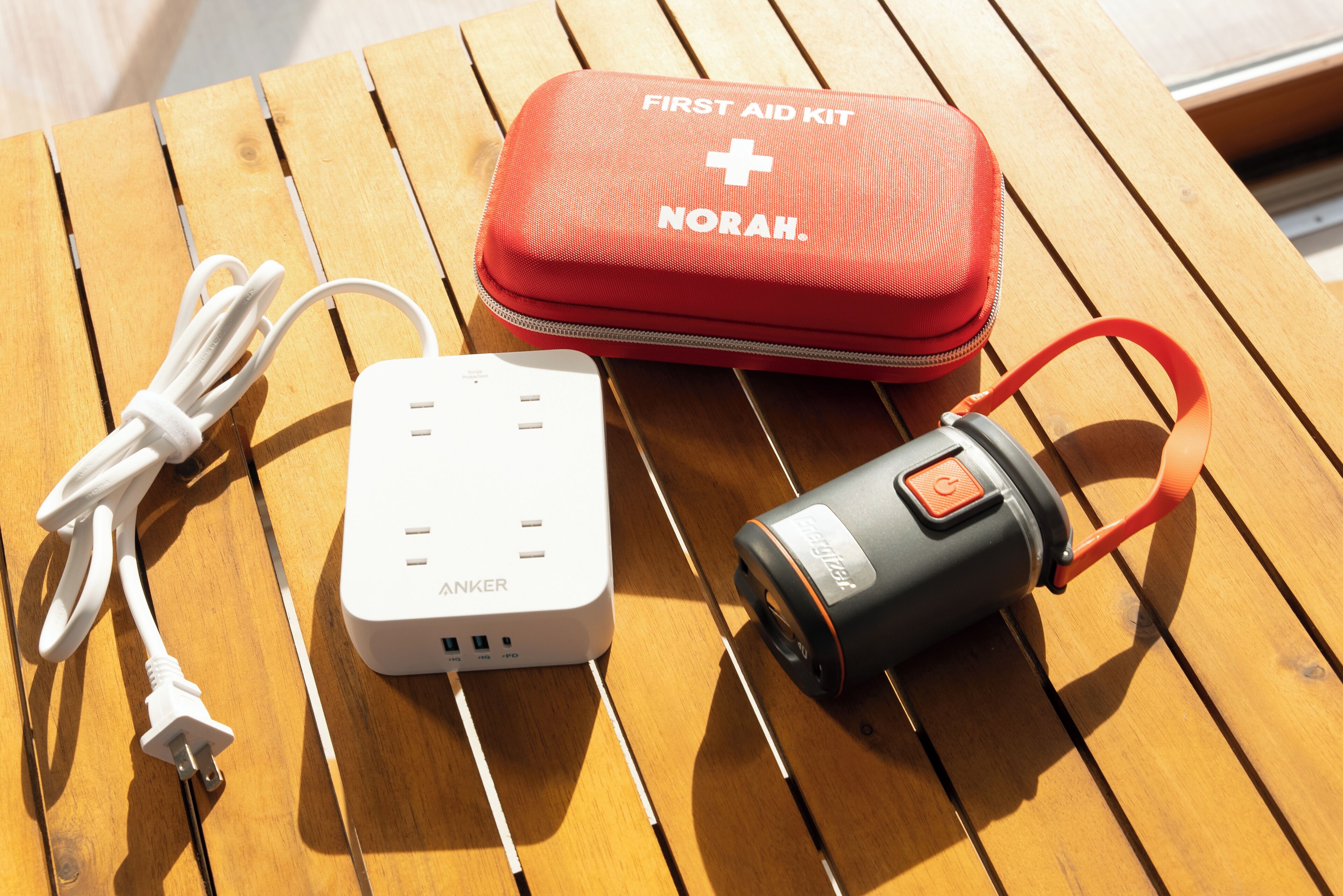 Ein Erste-Hilfe-Set, eine Powerbank und ein mobiler Ladegerät auf einer Holztisch.