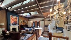 A spacious living area with a fireplace, a sofa, a dining table, and a chandelier. - Luxurious Rooftop French Quarter Penthouse (New Orleans)