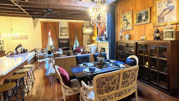 A dining area with a wooden ceiling, a chandelier, and a table set for four. - Luxurious Rooftop French Quarter Penthouse (New Orleans)