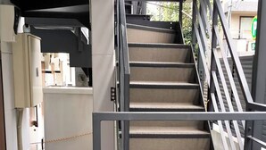 A staircase with metal railings and beige carpeted steps, leading to an upper floor.