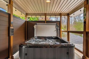 Ein Whirlpool in einem überdachten Außenbereich mit Holzwänden und Blick auf die Straße.