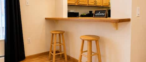 A kitchen with wooden cabinets, a built-in shelf, and two wooden stools.