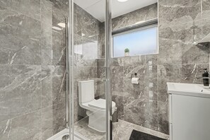 A bathroom with a glass-enclosed shower, a toilet, and a sink. - Modern 3 bed house in Edmonton with driveway parking (London)