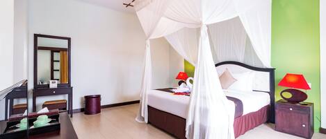 Habitación de hotel con cama, lámparas de noche, mesita de noche, espejo, cómoda y basurero.