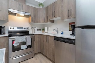 Una cocina moderna con electrodomésticos de acero inoxidable, armarios de madera y horno empotrado.
