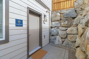 Entrada de hotel con pared de piedra, una puerta y un letrero azul que indica la ubicación.
