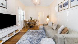 Ein Wohnzimmer mit Fernseher, Sofa und Essbereich.